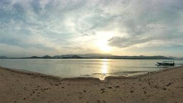 Una playa con un bote y montañas a lo lejos.