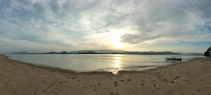 A beach with a boat and mountains in the distance.