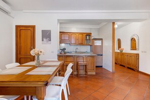 Une cuisine avec des meubles de rangement en bois, un pare-feu en carrelage et un coin repas comprenant une table et des chaises en bois.
