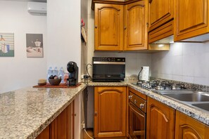 A kitchen with wooden cabinets, a built-in microwave, a gas stove, and a coffee maker. - Apartment 'Bentu E Mare' with Sea View, Wi-Fi and Air Conditioning (Alghero)