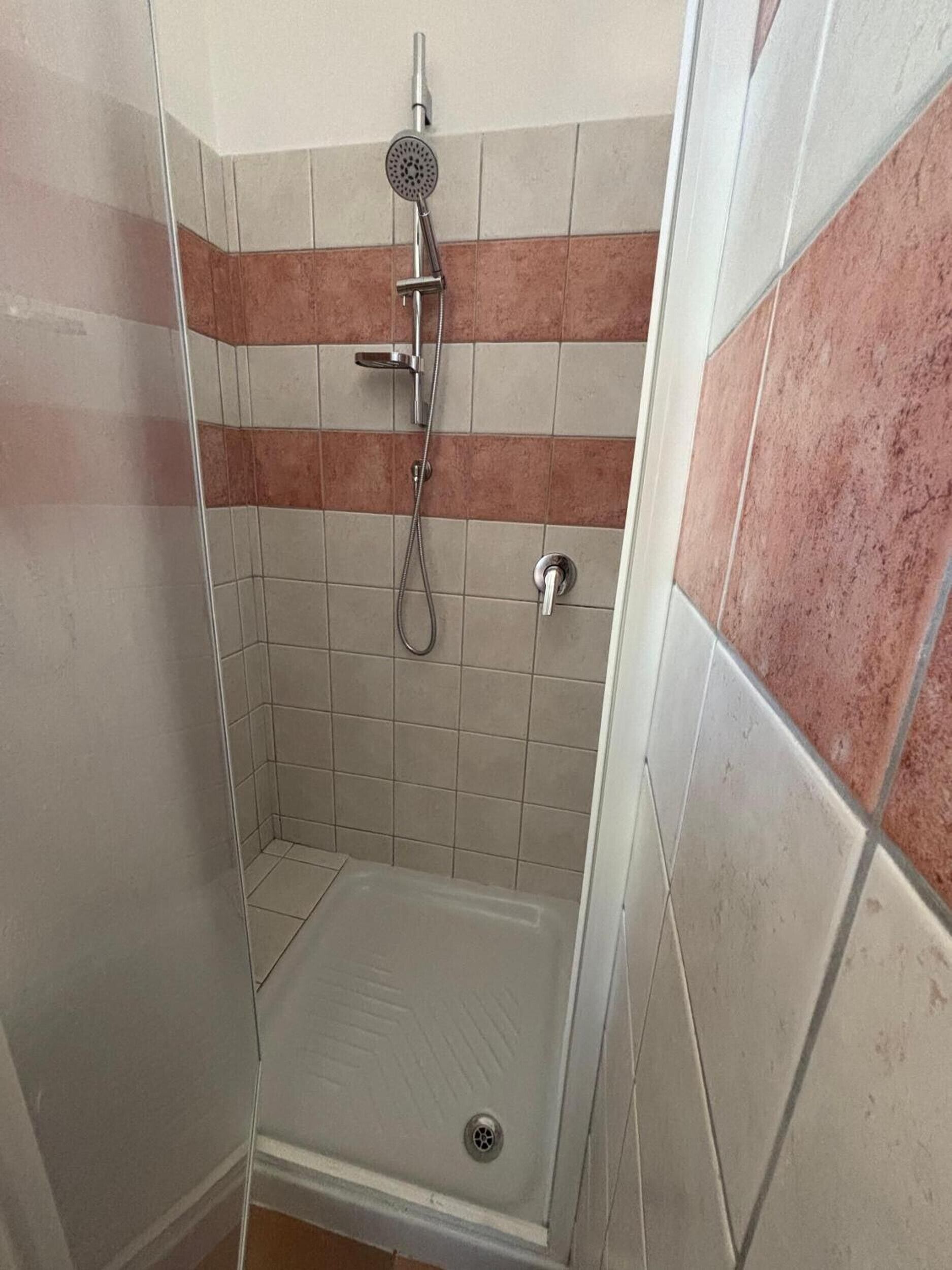 Eine Dusche mit Handbrause und Wandarmatur.