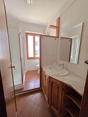 Un bagno con doccia, WC e lavandino.