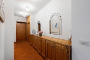 Un couloir avec des armoires en bois, un miroir et un vase rempli de fleurs.
