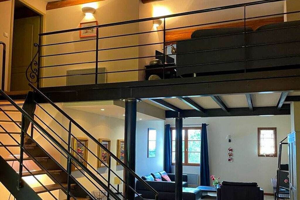 Interior com vários níveis, incluindo uma escada, um sofá e uma sala de jantar.