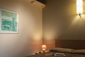 A bedroom with a bed, a bedside lamp, a nightstand, a framed picture on the wall, and a wall-mounted light fixture. - with loft flair in Bonnieux - 642 BON (Bonnieux)