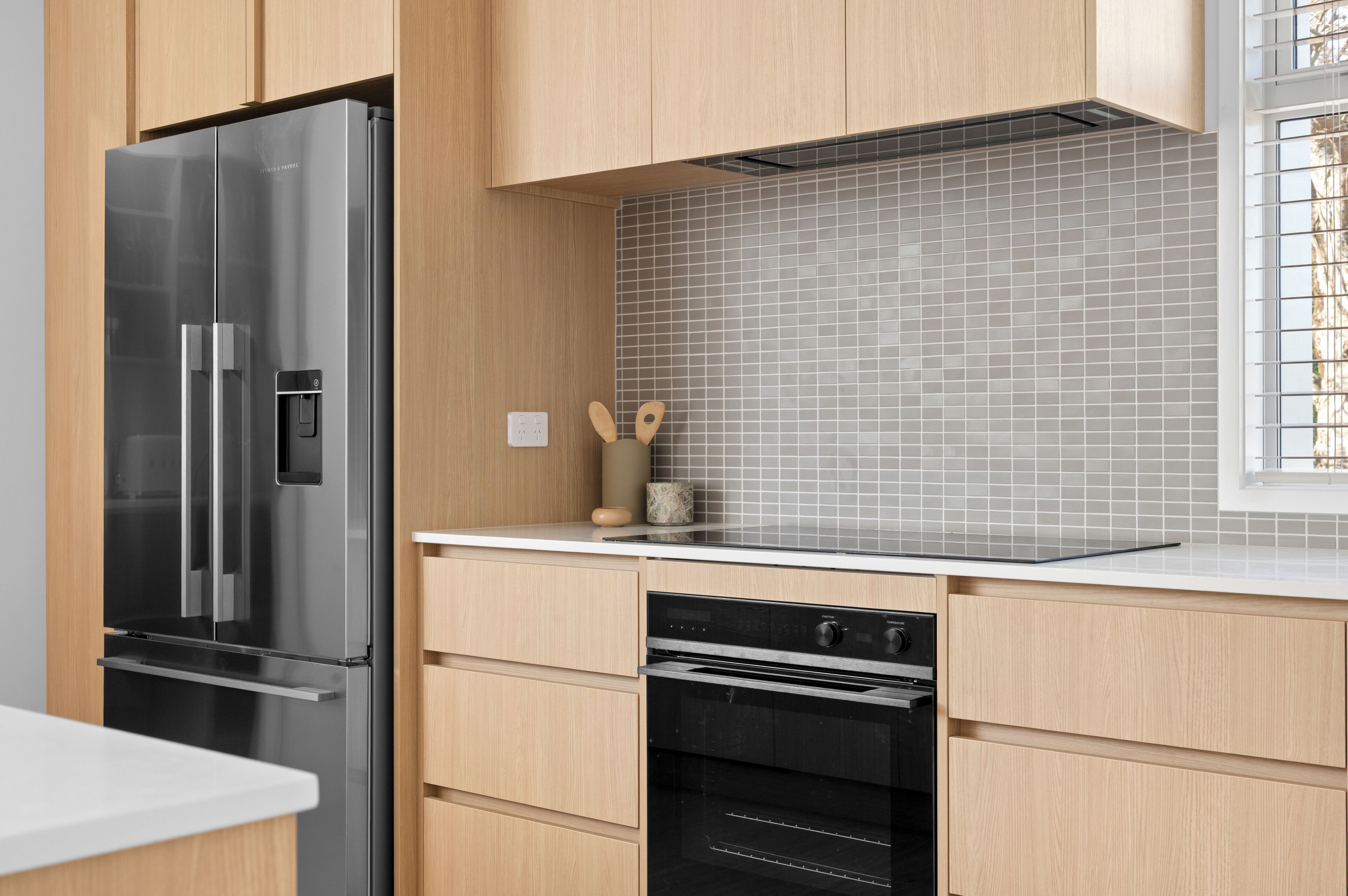 A modern kitchen with a stainless steel refrigerator, a dishwasher, and a tiled backsplash.