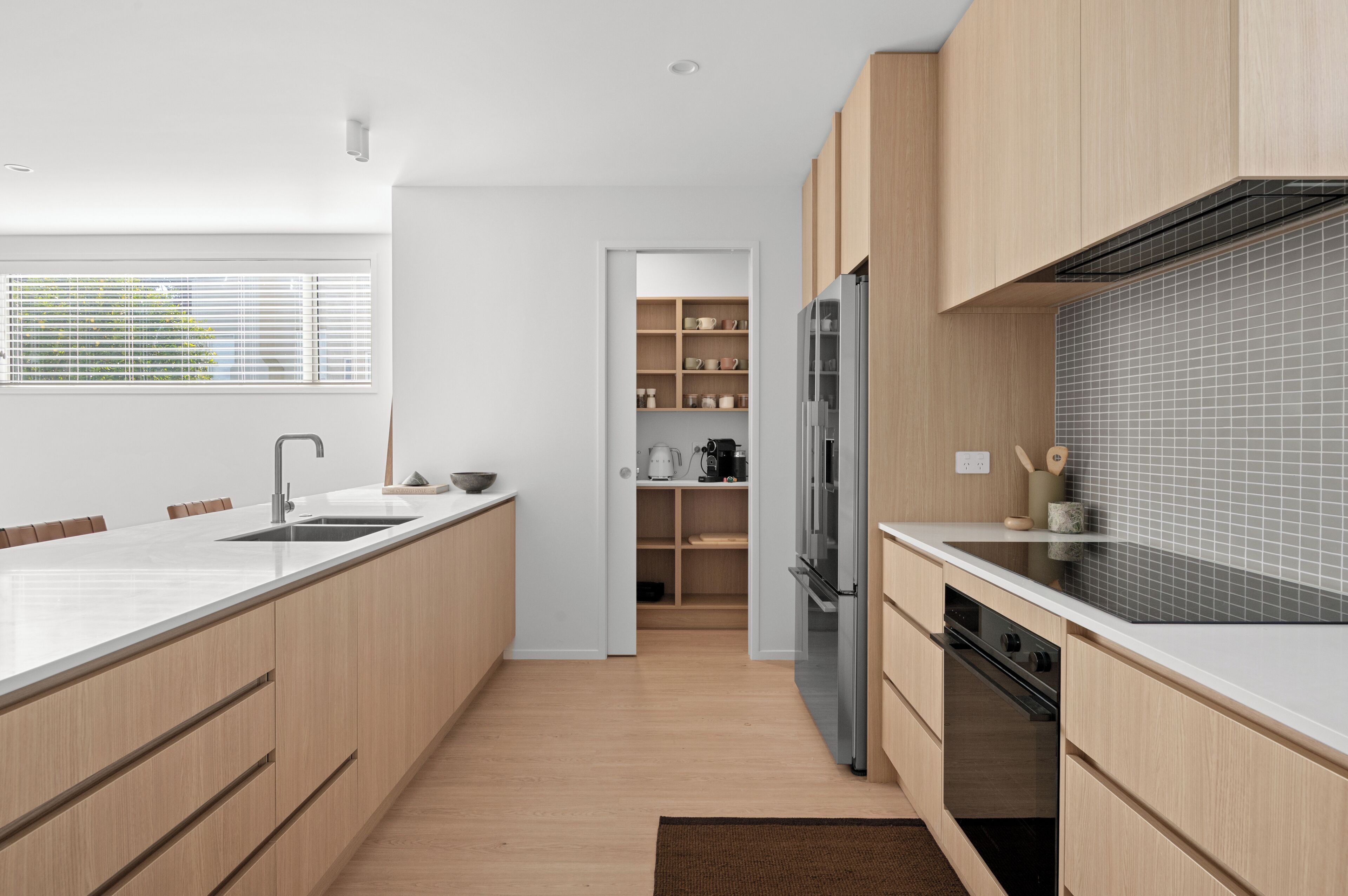 A modern kitchen with a large island, stainless steel appliances, and light wood cabinetry.