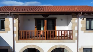 A two-story building with a balcony, arched windows, and a tiled roof. - Sierra Pando. Valdhaya Homes (Cantabria)