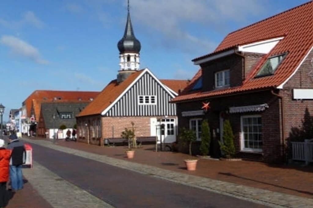 A street with traditional buildings, including a church with a pointed steeple.