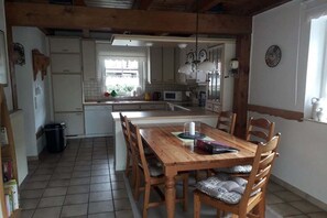 Une cuisine avec une table et des chaises en bois, un four à micro-ondes et une fenêtre.