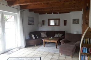 Un salon comprenant un canapé, un fauteuil, une table basse et une bibliothèque.