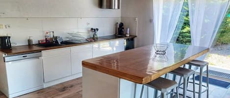 A modern kitchen with a wooden countertop, stainless steel appliances, and a bar area with stools.