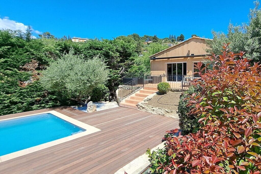 A residential property with a swimming pool, wooden deck, and a house with a balcony.