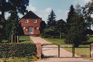 A brick house with a front door, a pathway leading to it, and a metal gate.