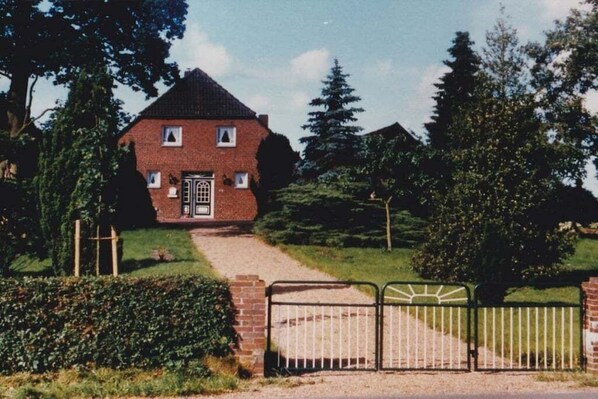 A brick house with a front door, a pathway leading to it, and a metal gate.