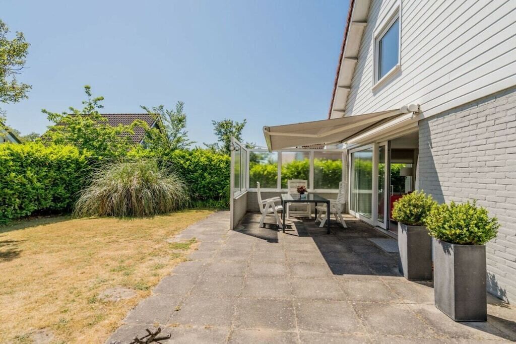 A patio area with a table and chairs, a covered seating area, and potted plants.