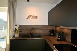 Eine moderne Küche mit einer dunklen Holz Arbeitsplatte, einer integrierten Spüle und einer Kaffeemaschine.