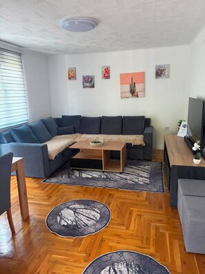 Een moderne woonkamer met een modulaire bank, een salontafel en een flatscreen televisie.