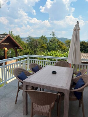 A patio with a table and chairs, a white fence, and a view of the landscape. - Private Family House with Garden & Gazebo Sleeps 10 Sarajevo (Sarajevo)
