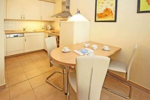 Una cocina compacta con una mesa y sillas, una cafetera y un hervidor.