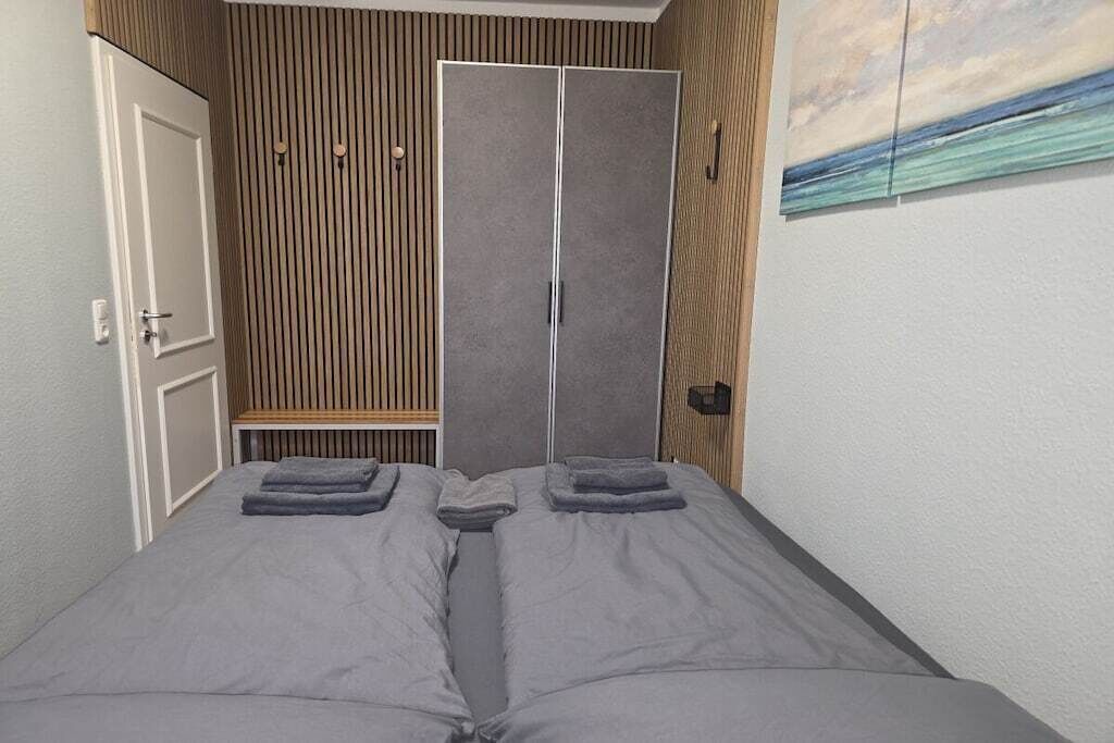 A bedroom with a bed, a bench, and a wardrobe.