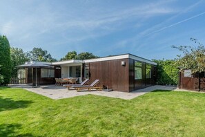 A modern house with a patio area, a dining table, and lounge chairs. - "t Ongerepte 56 - De Zandbank (Renesse)