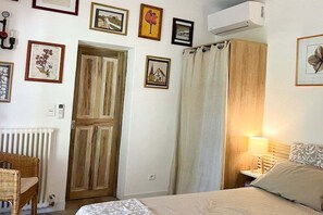 A bedroom with a bed, a wooden wardrobe, a radiator, and a wall-mounted air conditioner. - Holiday home in Aups with swimming pool (Aups)