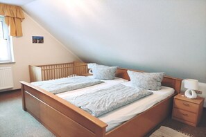 Een slaapkamer met een houten bed, twee kussens, een nachtkastje met een lamp en een raam met gordijnen.