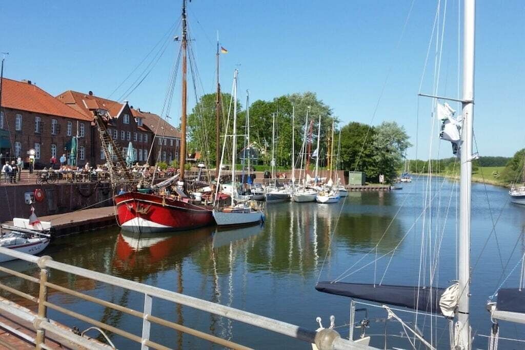 Een jachthaven met aangemeerde boten, een gebouw met rode daken en een heldere lucht.