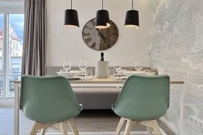 Un comedor con un reloj de pared redondo, lámparas colgantes y vistas de un edificio.