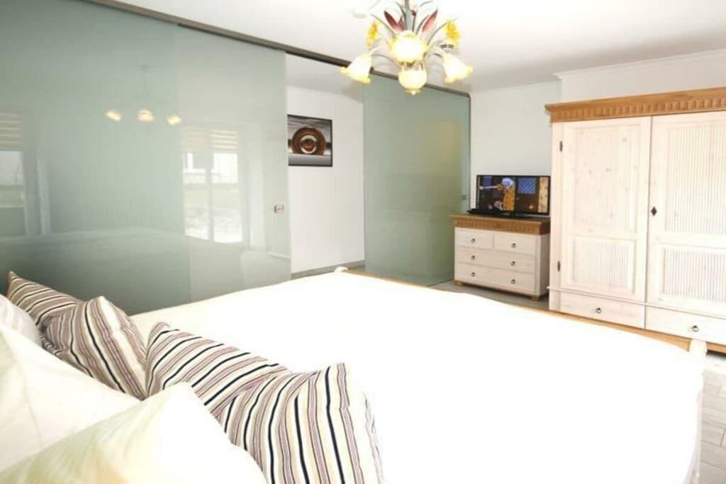 Een slaapkamer met een bed, een dressoir, een televisietoestel en een kledingkast.