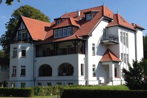 Un edificio grande de varios pisos con fachada simétrica, numerosas ventanas y tejado de tejas rojas.
