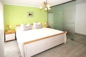 Un dormitorio con una cama grande, una mesita de noche con lámpara y un cuadro colgado en la pared.