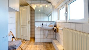 Een kleine badkamer met een wastafel, spiegel en houten vloer.
