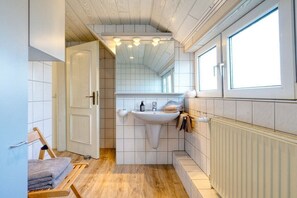 Une petite salle de bain avec un lavabo, un miroir et un plancher en bois.