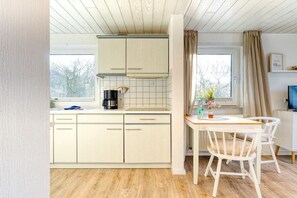 Een keuken met witte kastjes, een koffiezetapparaat en een eettafel met stoelen.