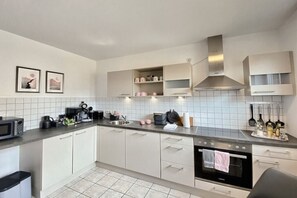 A modern kitchen with white cabinets, a built-in oven, and a microwave. - Holiday home in Rees with swimming pool (Rees)