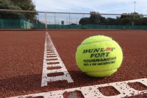 Une balle de tennis sur un court en terre battue, avec des lignes blanches délimitant le terrain.