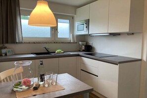 Een moderne keuken met een raam, een magnetron en een koffiezetapparaat.