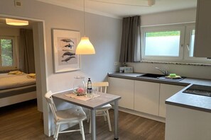 A compact living space with a kitchenette, a dining area, and a bed. - Holiday apartment with 2 bedrooms (Norderney)