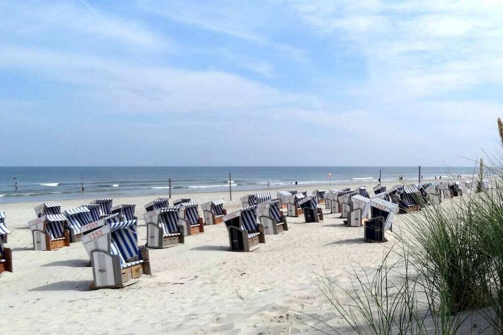 Una playa con hileras de sillas y sombrillas a rayas.