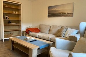 Ein Wohnzimmer mit einer Couch, einem Couchtisch und einem Bücherregal.