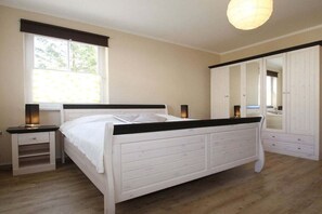 Un dormitorio con cama, mesitas de noche, un armario y una ventana.