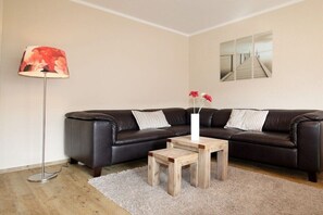 A living room with a dark leather sofa, a wooden coffee table, a floor lamp, and a mirror on the wall. - Holiday apartment Strandstraße 43 319568 (Kühlungsborn-Ost)