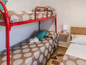 Ein Etagenbett mit einem gemusterten Bettbezug, ein Nachttisch mit Lampe und ein Holz-Kopfteil.