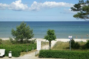 A beach with a clear view of the sea, a pathway leading to the beach, and a signpost with information. - 3 (Beach Magic) in Villa Helene (Ostseebad Binz)