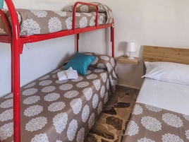 Una cama litera con un edredón estampado, una almohada color aguamarina y una toalla blanca en la cama inferior.