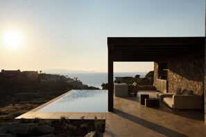 Ein moderner Poolbereich im Freien mit Blick auf das Meer und entfernte Gebäude.