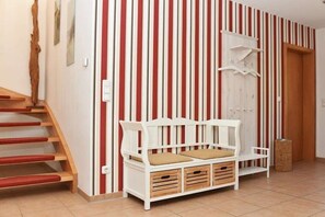 A staircase with red steps, a white bench with storage drawers, and a striped wall. - Holiday home with 2 bedrooms (Born auf dem Darß)