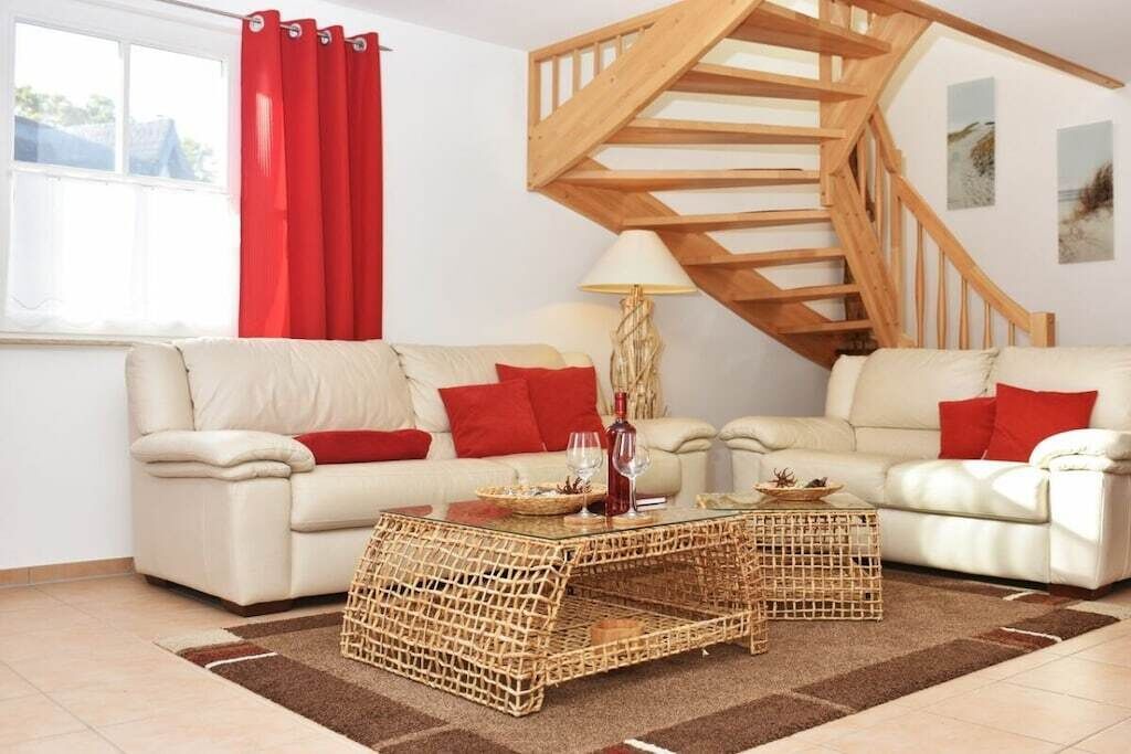 Una sala de estar con dos sofás, una escalera de madera y una mesa de centro de cristal.